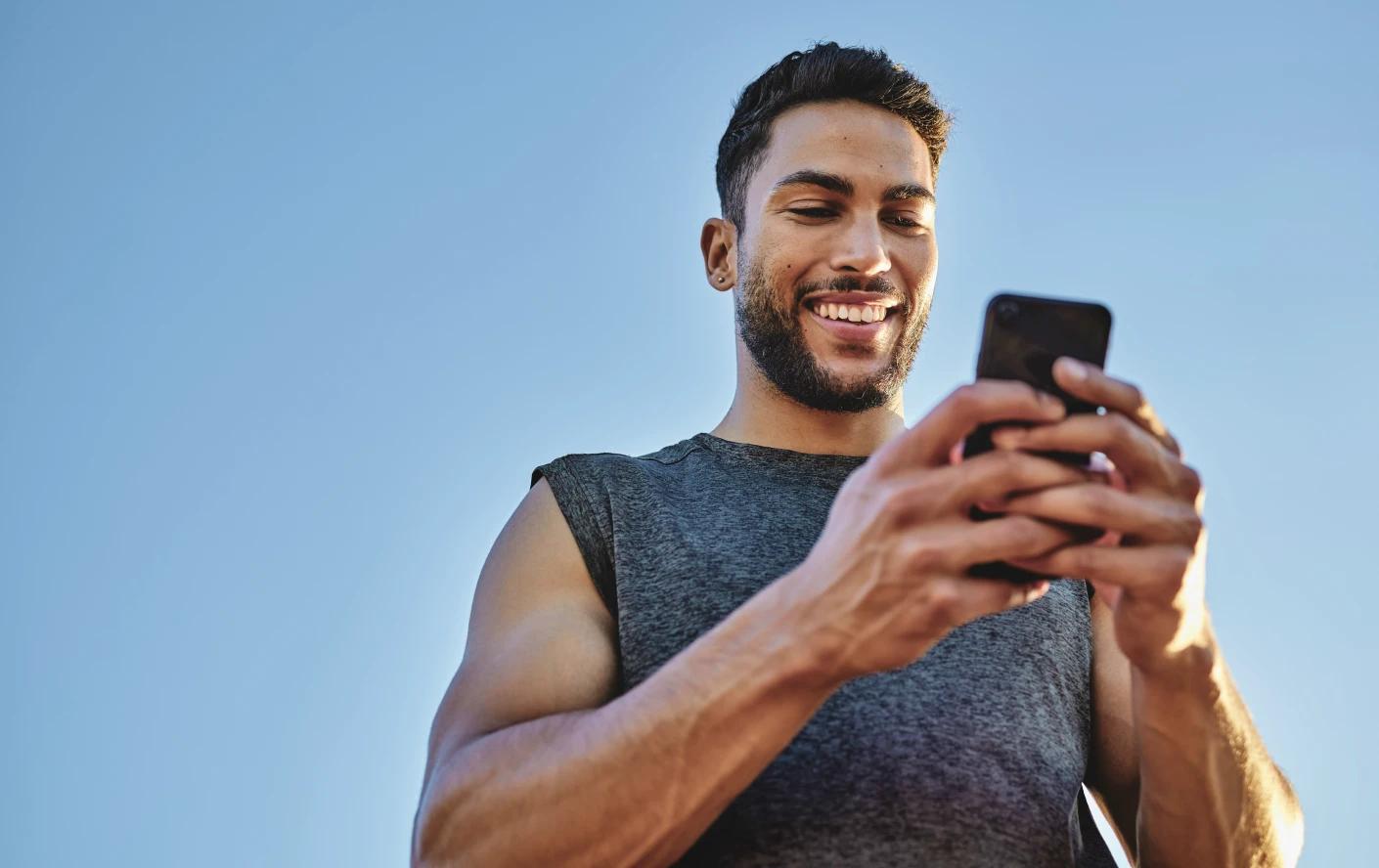 A imagem tem um homem mais jovem mexendo no celular. 