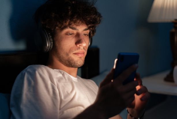 homem mexendo no celular na cama