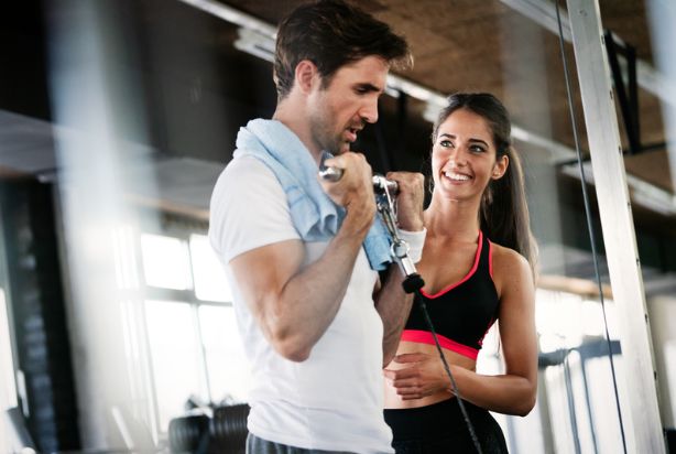 personal trainer ajudando aluno na academia