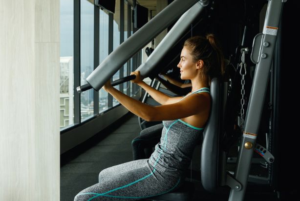 mulher fazendo supino máquina na academia