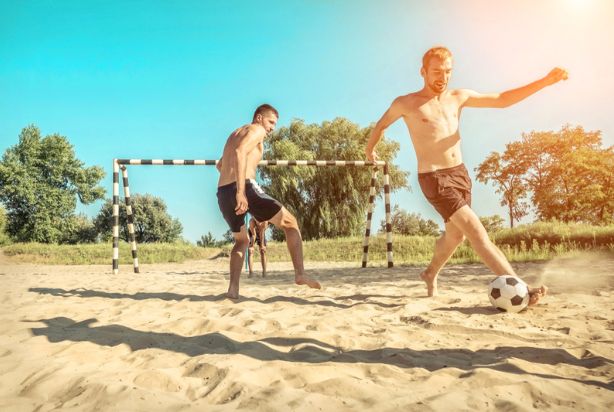 pessoas jogando futebol de areia na praia